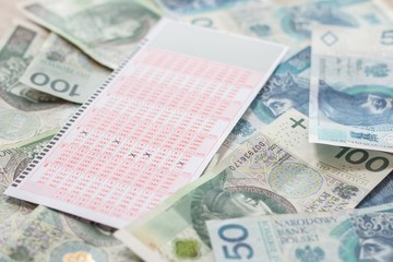 Wygrana w lotto. Pieniądze leżą na stole a kupon ze szczęśliwymi liczbami leży na gotówce.