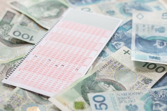 Wygrana w lotto. Pieniądze leżą na stole a kupon ze szczęśliwymi liczbami leży na got&oacute;wce.