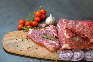 raw meat and vegetables on cutting board on dark cement background