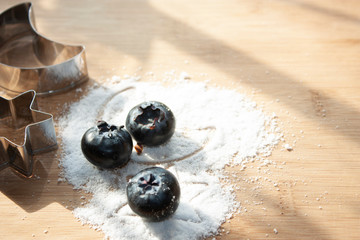 Blueberries among moon star figures pose on sugar-free sweet granules for dessert on wooden table...