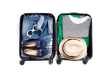 Flat lay with open suitcase with casual clothes for summer vacations over white background. Summer...