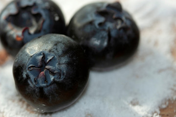 Juicy Blueberries jumbo macro on sugar-free .aspartame bed on wood.