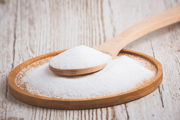 White sea salt for cooking food in Small glass bottles, wooden spoons, and trays on Old wooden table Background.