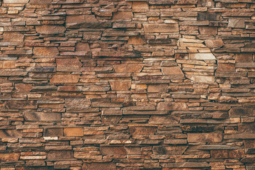 Abstract pattern of brown stone texture. Brick wall background. Rough granite surface. Cracked rock. Decorative tile on facade of building.