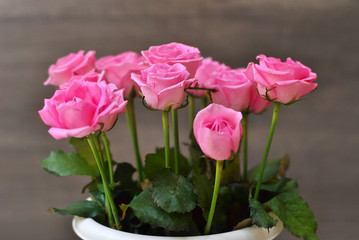 Beautiful lush bouquet of pink roses flowers on the wooden background. Stylish floristic composition in the long vertical vase. Spring time and holidays concept, interiors decorating