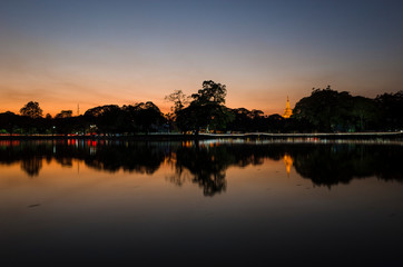 Shwedagon golden Pagoda reflecting in Kandawgyi Lake at dusk in Bogyoke Park. Yangon, Myanmar