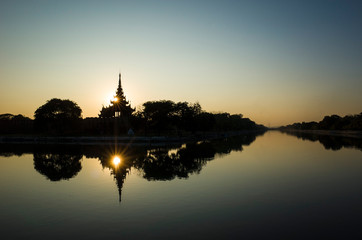 Fototapeta na wymiar Mandalay Palace wall and moat picturesque silhouette with twilight sky in sunset with sun reflection in water, Myanmar
