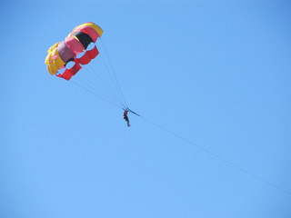 Parasailing water amusement. Beautiful bright blue sky and colorful parachute