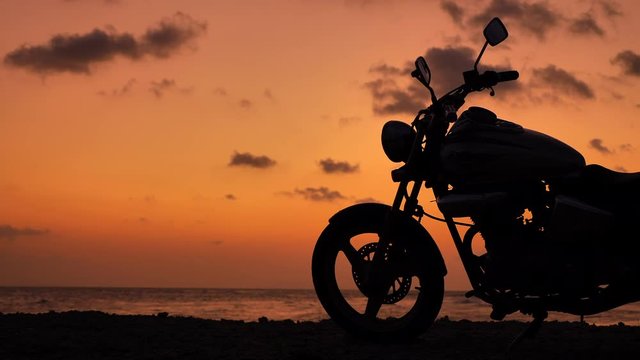 Motorcycle silhouette at sunset time near sea coast