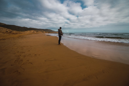 Hombre contemplando las olas del mar en la orilla de la playa