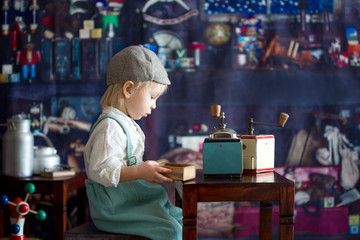 Little toddler boy, playing with mill at home, sitting on vintage table
