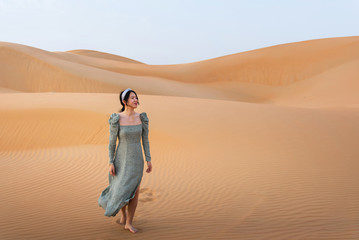 Fototapeta na wymiar Woman walking on the desert sand dunes