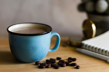Black coffee in Blue cup on freshly roasted coffee beans background. Top view.