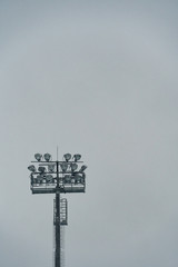 Large outdoor football stadium spotlight tower isolated on snowy day. Sports event concept. Copyspace.