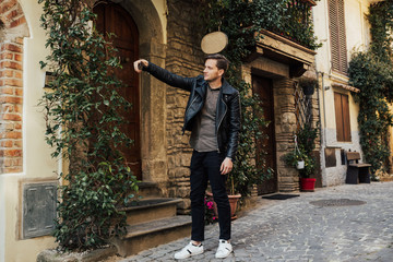 Cheerful man making selfie on the street of Italy. Man taking a selfie while walking around a old city street.