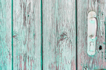 Rusty handle on wooden door with cracked peeling green paint. Texture of weathered painted wood with copy space for your design. Blank template