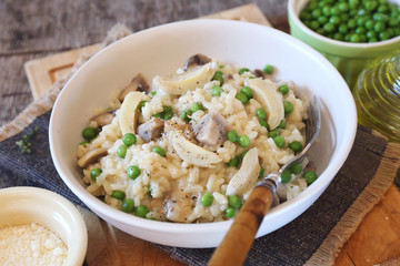 Italian cuisine. Plate of mushroom risotto with green pea, artichokes and grated parmesan cheese