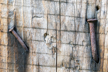 Texture of old weathered cracked board with rusty nails driven in with smudges close up