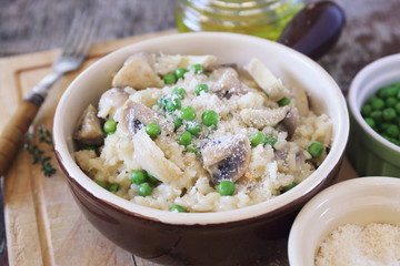 Italian cuisine. Plate of mushroom risotto with green pea, artichokes and grated parmesan cheese
