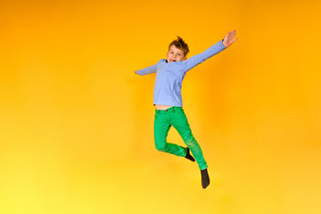 Fototapeta na wymiar Joyful and happy boy expresses his emotions in a jump, a child is jumping on a yellow background.