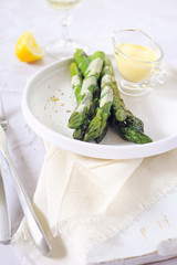 French cuisine. Fresh green asparagus with hollandaise sauce and glass of white wine