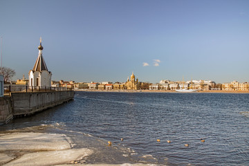 The embankment of the Neva with a church on one shore and cathedral on another, remnants of ice...