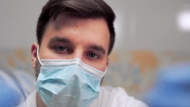 Young handsome dentist treats camera, closeup