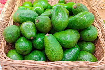 A lot of avocados in a wicker basket. Fruit on the counter in the store. Fruit retail sale concept.