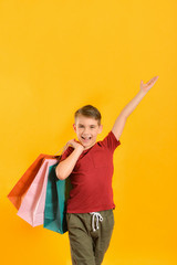 Boy with shopping bags on a yellow background, shopping concept.