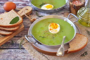Green pea soup with spinach, olive oil, sesame and half boiled egg dressing in two bowls