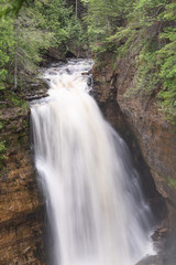 Silky smooth water of Miners Fall at Pictured Rocks National Lakeshore  rushing over rocks and plunging to canyon below