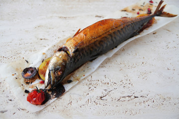  grilled whole mackerel with spices and herbs. Served on a marble table with vegetables,...