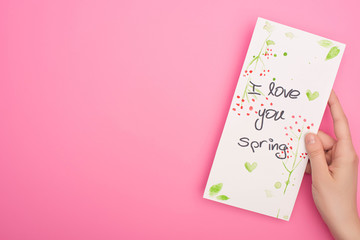 Partial view of card with I love you spring lettering in woman hand on pink background