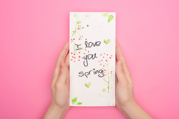 Partial view of woman holding card with I love you spring lettering on pink background