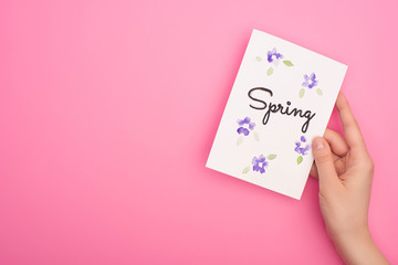 Partial view of woman holding card with spring lettering on pink background