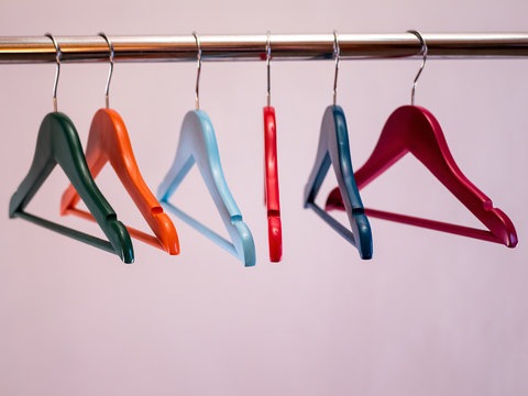 row of colored hangers sway on metal shiny clothes rail isolated on white background