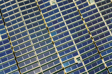 Aerial view of many photo voltaic solar panels mounted of industrial building roof.