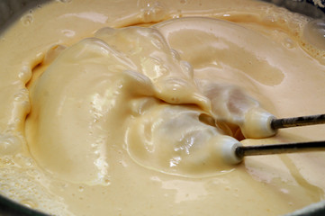 A Cup of batter for making pancakes. The process of mixing the dough with a mixer.Close up..