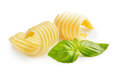 Butter curls or butter rolls with basil leaves isolated on white background - obrazy, fototapety, plakaty