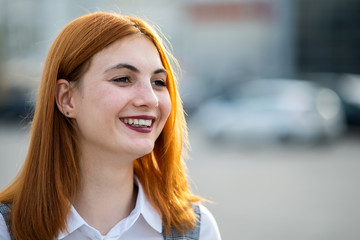 Closeup face portrait of a smiling teenage girl with red hair and clear eyes.