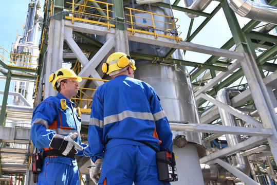 group of industrial workers in a refinery - oil processing equipment and machinery