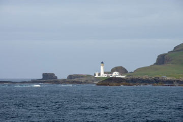 Lighthouse on small island at sea in Scotland, United Kingdom.