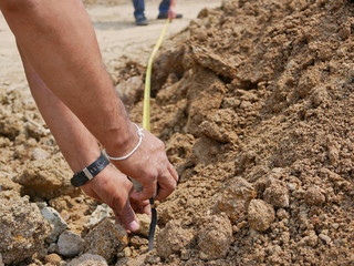 Hands of a man holding a measuring tape checking the length of land during a survey