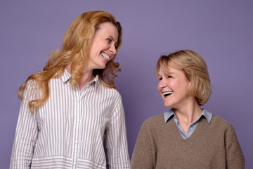 Two happy mature women sisters laughing and smiling looking at camera.