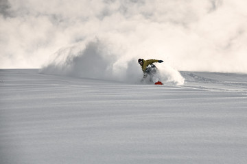 Man on a snowboard slides on a snowy mountain side