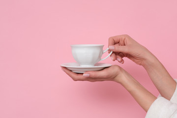 Coffe please. Female hand holding a cup of coffee isolated on pink background. Time to charge battery.