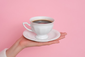 Coffe please. Female hand holding a cup of coffee isolated on pink background. Time to charge battery.