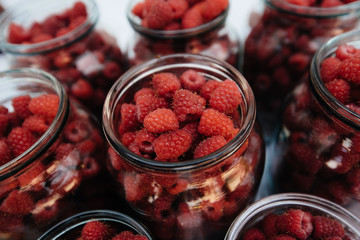 Fresh, ripe raspberries in small jars close-up