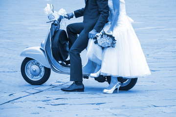 Young newlywed just married, posing on an old gray scooter. Classic Blue Pantone 2020 year color.