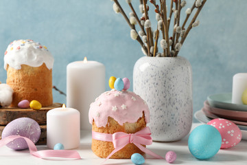 Easter concept with Easter cakes and candles on wooden table against blue background